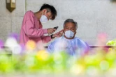 Un résident confiné se fait couper les cheuveux par un volontaire dans le disctrict de Pudong à Shanghai le 1er mai 2022