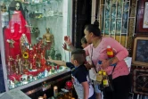 Une femme et ses enfants touchent une vitre devant une représentation de la "Santa Muerte" dans une rue du quartier de Tepito, le 1er octobre 2020 à Mexico