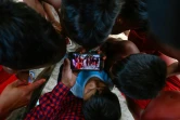 Des enfants de la tribu Waiapi regardent sur un smartphone une vidéo d'une danse traditionnelle Waiapi, dans leur village de Manilha le 12 octobre 2017