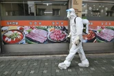 Un employé sud-coréen vêtu d'une combinaison de protection contre le coronavirus désinfecte une rue à Séoul le 18 août 2020.