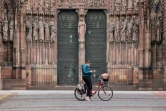 Une cycliste s'arrête pour consulter son téléphone, devant la cathédrale de Strasbourg, en mars 2020
