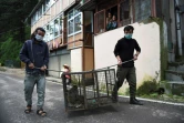 Des employés des services de protection de l'environnement transportent dans une cage deux singes capturés dans un quartier résidentiel de Shimla, le 30 août 2020 en Inde