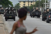 Une femme regarde les soldats ivoiriens qui patrouillent près du quartier général de l'armée, le camp militaire de Gallieni, à Abidjan le 12 mai 2017 
