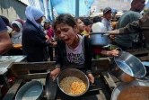 Une fillette reçoit de la nourriture tandis que d'autres Palestiniens attendent à un point de distribution de repas à Nousseirat, dans le centre de la bande de Gaza, le 2 juin 2025