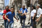 Un volontaire de la Défense civile syrienne porte un enfant blessé par les bombardements à Alep le 23 juillet 2016