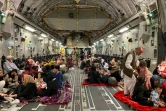 Des Afghans s'installent dans un avion militaire américain qui va les évacuer d'Afghanistan, à l'aéroport de Kaboul, le 19 août 2021