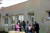Des salariés de l'équipementier automobile creusois GM&S, devant le site de la Souterraine où est inscrit un graffiti "283 familles sacrifiées par des patrons voyous" 