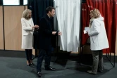Le président français Emmanuel Macron et son épouse Brigitte Macron s'entretiennent avec une électrice avant de voter au premier tour de la présidentielle, le 10 avril 2022 au Touquet 
