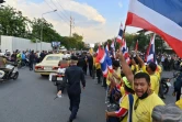 Des partisans pro-royalistes agitent le drapeau thaïlandais lors du passage du cortège royal, le 14 octobre 2020 à Bangkok 
