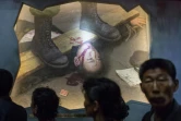 Un groupe de visiteurs passe devant un tableau représentant des soldats américains torturant un Nord-Coréen, le 24 juillet 2017 au Musée des atrocités de guerre américaines à Sinchon, en Corée du Nord