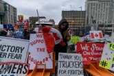 Un manifestant arrange des pancartes et un drapeau canadien, devant le Parlement à Ottawa, le 16 février 2022