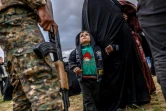 Un enfant regarde un combattant des Forces démocratiques syriennes après avoir quitté le dernier réduit du groupe Etat islamique à Baghouz, dans l'est syrien, le 27 février 2019