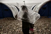 Une Irakienne qui a fui Mossoul se protège de la pluie dans le camp de Hammam al-Alil, le 13 mars 2017