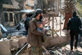 Un homme porte un enfant dans ses bras après une frappe aérienne sur Hamouria près de Damas au cours de laquelle au moins 16 civils sont morts et des dizaines de personnes ont été blessées, le 25 mars 2017