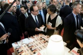 Le président François Hollande tenant un livre écrit par le candidat du mouvement "La France insoumise" à la présidentielle Jean-Luc Mélenchon, lors de la foire du livre à Paris, le 23 mars 2017