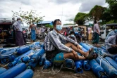 Un homme assis fait la queue pour remplir des bouteilles d'oxygène à Mandalay le 13 juillet 2021