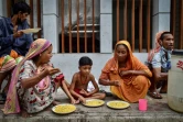 Des personnes apauvries par la crise du coronavirus mangent un repas offert par l'association Mehmankhana, le 26 juillet 2021 à Dacca