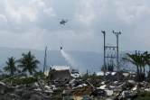 Photographie prise le 18 octobre 2018, à Palu en Indonésie, montrant un hélicoptère pulvériser du désinfectant au dessus de la zone dévastée par un tsunami le 28 septembre