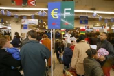 Des clients s'apprêtent à régler leurs achats aux caisses en euros (G) ou en francs, le 5 janvier 2002 dans un supermarché à La Défense, près de Paris