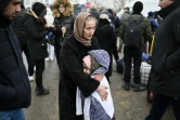 Une femme réconforte un enfant en attendant un mode de transport à un poste frontière entre la Moldavie et l'Ukraine près de la ville de  Palanca le 1e mars