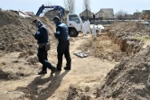 Des experts de l'Institut de Recherches criminelles de la Gendarmerie nationale (IRCGN) examinent une fosse commune, le 14 avril 2022 à Boutcha, au nord-ouest de Kiev, en Ukraine