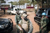 Un membre de la garde présidentielle, un paramilitaire russe et un Casque bleu de la Minusca accompagnent le président centrafricain dans un bureau de vote de Bangui le 27 décembre 2020