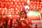 Une jeune femme en robe rouge de style chinois prie au temple Wat Mangkon Kamalawat dans le quartier chinois de Bangkok, à la veille de la nouvelle année lunaire du serpent, le 28 janvier 2025 en Thaïlande