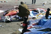 Un proche accroupi près d'un corps  d'une des victimes, recouvertes de drapeaux, du double attentat qui a fait au moins 86 morts à Ankara en Turquie, le 10 octobre 2015 