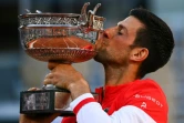 Le Serbe Novak Djokovic embrasse la Coupe des Mousquetaires après sa victoire en 5 sets face au Grec Stefanos Tsitsipas, le 13 juin 2021 au tournoi de Roland-Garros à Paris