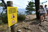 Des randonneurs à proximité d'une une pancarte indiquant l'interdiction d'accès à la plage de l'Ile Vierge à Crozon dans le Finistère, le 29 juillet 2021