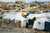 Un homme passe devant des tentes de déplacés installées près des bâtiments détruits à Bureij, dans le centre de la bande de Gaza, le 17 janvier 2025
