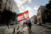 Un protestataire à Beyrouth brandit le drapeau national libanais devant les forces de sécurité pendant une manifestation le 8 août après l'explosion dévastatrice du 5 août