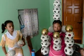 Han Myint Mo (g) regarde son grand-père Ohn Mynt d'un entraînement de jonglage, le 5 juillet 2022 à Rangoun, en Birmanie