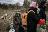 Des habitants attendent de pouvoir traverser un pont détruit pour quitter la ville d'Irpin, au nord-ouest de Kiev,  le 5 mars 2022