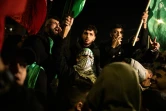 Des Palestiniens brandissant des drapeaux du Hamas attendent avec des membres de leur famille et des amis la libération de prisonniers détenus par Israël, à Baytunya, à l'extérieur de la ville de Ramallah en Cisjordanie, le 19 janvier 2025