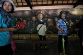 Des touristes photographient une fresque relatant le sauvetage des adolescents thaïlandais en 2018 à l'entrée de la grotte de Tham Luang, le 13 juin 2019 à Mae Sai