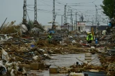 Des agents se tiennent au milieu des débris sous la pluie à Paiporta, au sud de Valence, dans l'est de l'Espagne, le 13 novembre 2024