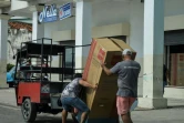 Deux hommes portent un réfrigérateur acheté dans une boutique de La Havane, le 15 septembre 2020 à Cuba