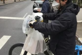 Un livreur porte masque, gants et sacs en plastique pour se protéger les mains sur son vélo, le 17 mars 2020 à New York
