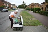 Sheila, 71 ans, récupère ses courses transportées jusque chez elle par un robot autonome, appelé Starship, à Milton Keynes, en Angleterre, le 20 septembre 2021