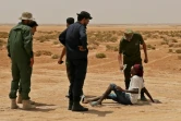 Des gardes-frontières libyens donnent à boire à des migrants africains à leur arrivée à la frontière entre la Libye et la Tunisie, près d'Al'Assah, le 30 juillet 2023