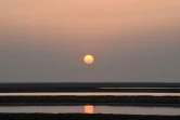 Le soleil couchant se reflète le 8 janvier 2021 dans un marais salant à Kharaghoda, en Inde