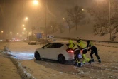 Des pompiers poussent une voiture bloquée par la tempête de neige à Madrid, le 9 janvier 2021