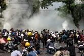 Des manifestants se mettent à couvert pendant des tirs de gaz lacrymogènes par la police, le 3 mars 2021 à Mandalay, en Birmanie