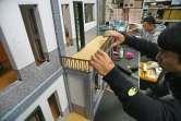 Un employé d'une société spécialisée dans la fabrication d'offrandes en papier fixe le balcon d'une maison, le 7 mars 2019 à Taïwan