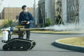 Un employé commande un robot pour désinfecter des rues à Hangzhou dans l'est de la Chine, le 25 février 2020