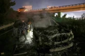 Des policiers inspectent l'épave d'un véhicule calciné de la Finul, incendié par des manifestants, sur la route menant à l'aéroport de Beyrouth, le 14 février 2025 au Liban