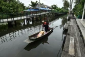 Nopadol, postier, distribue des lettres et colis aux habitants vivant sur les bords d'un canal dans la province de Bang Khun Thian, près de Bangkok en Thaïlande, le 17 juillet 2017
