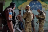 Des policiers vérifient l'identité de deux hommes pendant une opération contre le trafic de drogue dans la favela de Jacarezinho, le 19 janvier 2022 à Rio de Janeiro, au Brésil
