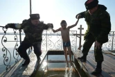 Des cosaques aident un garçon à se baigner dans des eaux glaciales d'un lac pour célébrer la fête orthodoxe de l'Epiphanie près du village de Pokrovka, à 15 kilomètres de Bichkek en Kirghizie